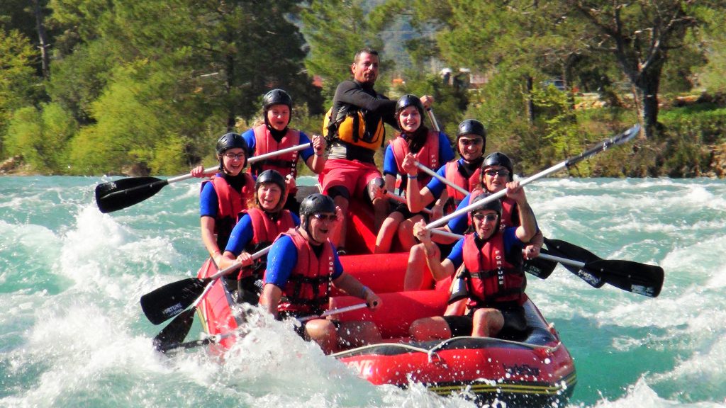 Rafting botlarındaki maceraperestler heyecanlı bir şekilde nehrin akıntısını takip ederler.
