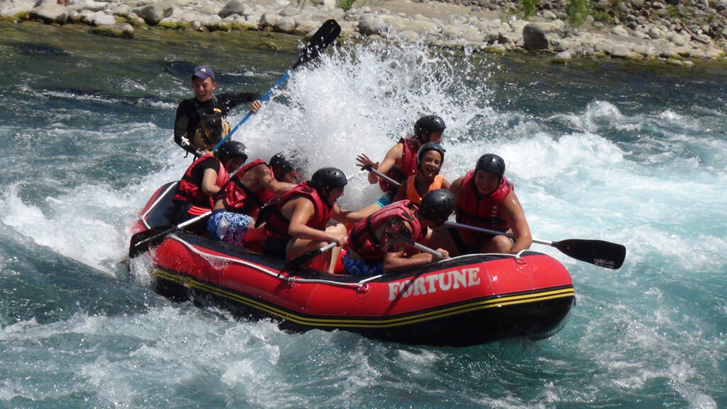 Nehirde rafting yapanlar, profesyonel bir rehber eşliğinde macera dolu anların tadını çıkarır.